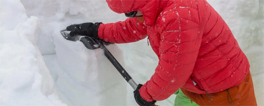 Mountain guide assessing avalanche risk with shovel during thrilling winter freeriding adventure